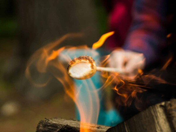 A marshmallow on a stick over a campfire.