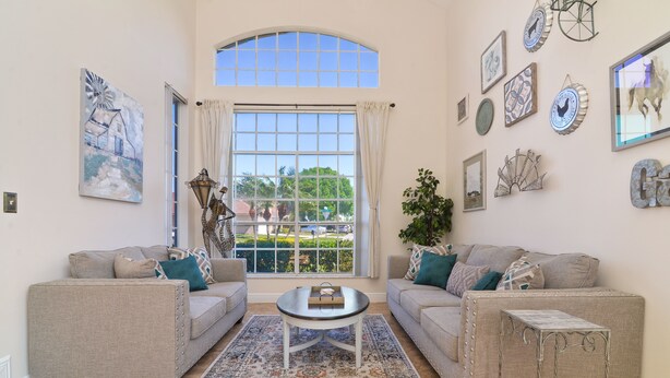 Ein Wohnzimmer mit zwei Sofas, einem Couchtisch und einem großen Fenster mit Vorhängen.