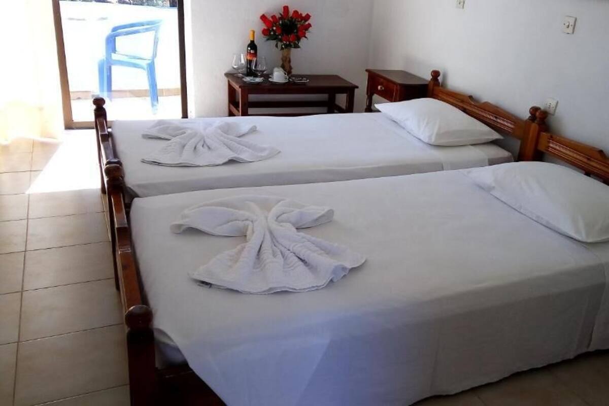 A hotel room with two beds, each with neatly folded white towels and a wooden headboard.