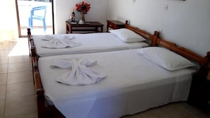 A hotel room with two beds, each with neatly folded white towels and a wooden headboard. - Anthoula Sun (Rhodes)
