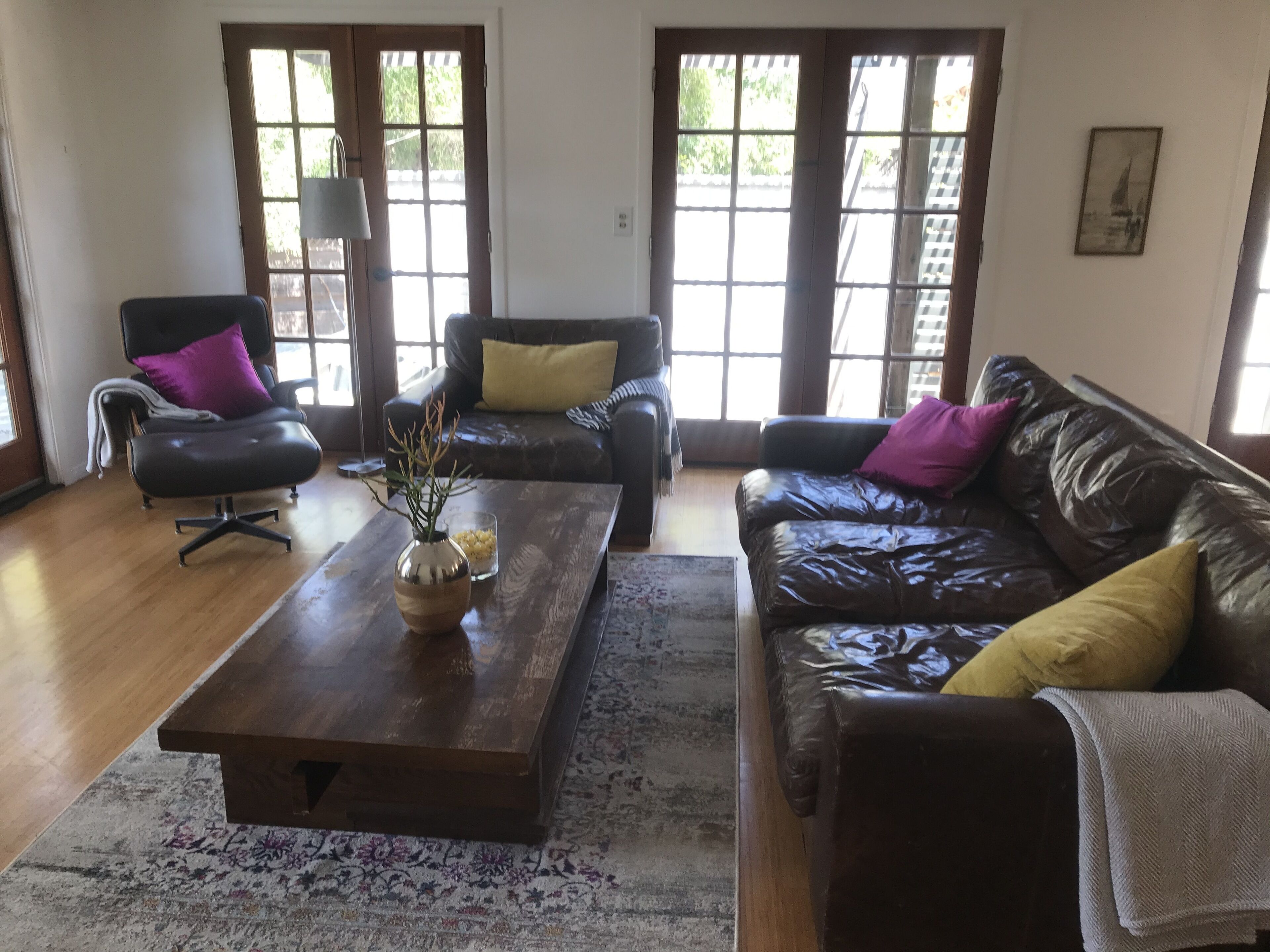 A living room with a wooden coffee table, two leather sofas, and a chair.