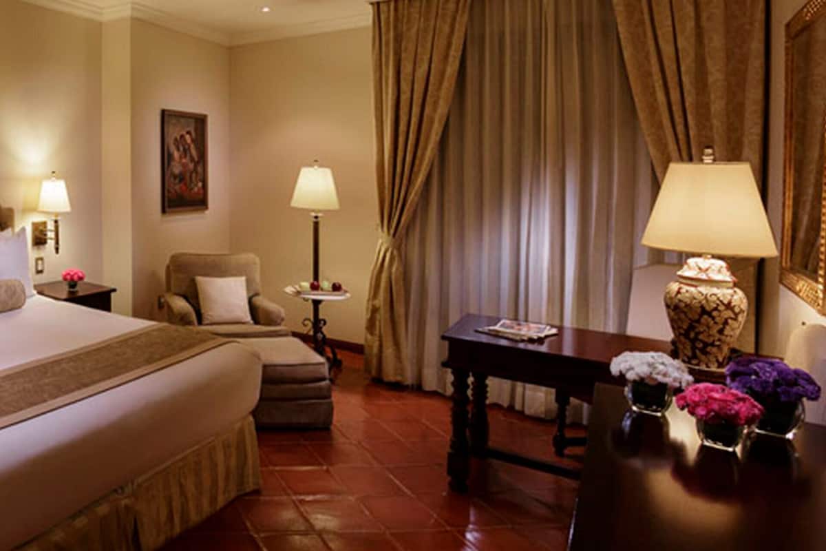 Una habitación de hotel con una cama grande, un espacio para sentarse, un escritorio y vistas al exterior.