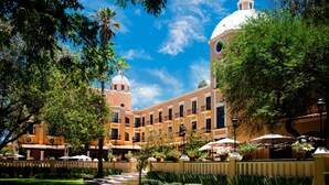 A courtyard with a building featuring a dome and a bell tower, surrounded by lush greenery and outdoor seating areas. - Villa Antigua (Tequisquiapan)