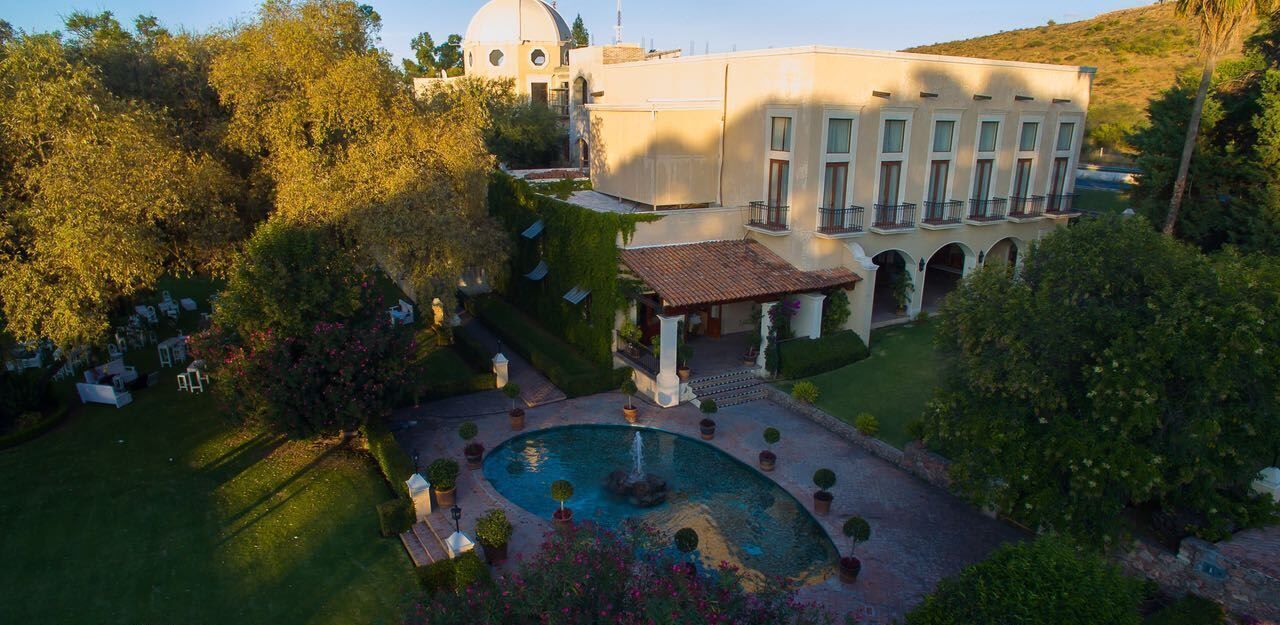 Un edificio grande con un patio, una fuente y una piscina.