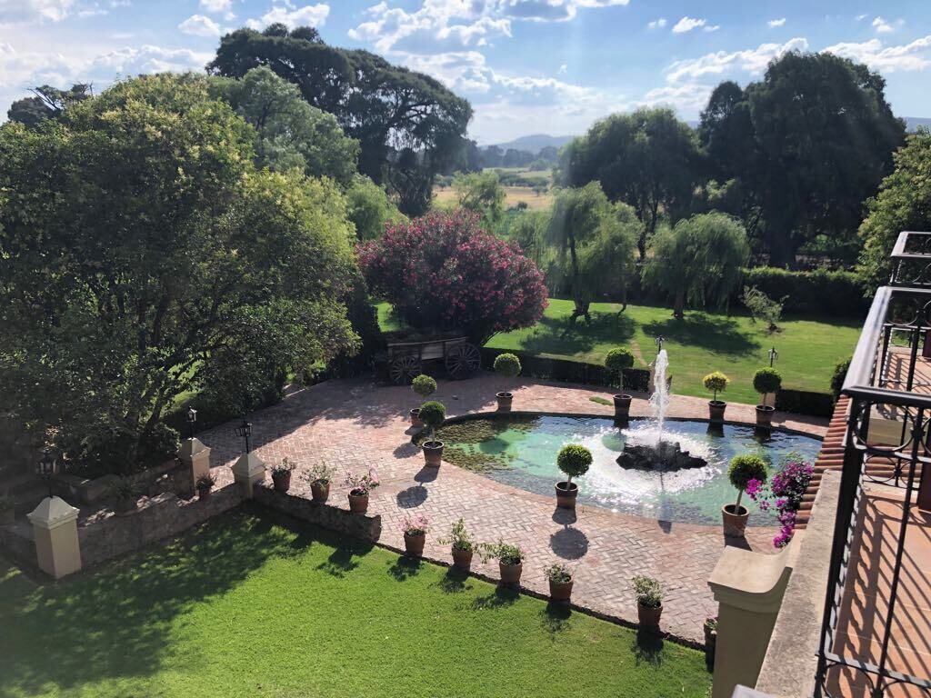 Un patio con una fuente, plantas en macetas y vistas del paisaje circundante.