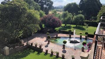 Un patio con una fuente, plantas en macetas y vistas del paisaje circundante.