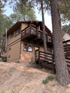 Stunning two-story building with a balcony and wooden fence, set amidst a serene natural backdrop.