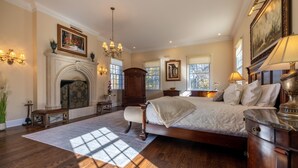 A spacious bedroom with a large bed, a fireplace, and a chandelier.