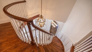 A wooden staircase with white railings and a chandelier.