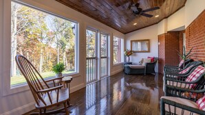 A spacious room with large windows, wooden flooring, and a ceiling fan.