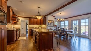 A spacious kitchen with wooden cabinets, a large island, and a dining area with a table and chairs.