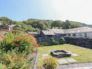 A stone building with a grassy yard and a fire pit.