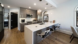 Een moderne keuken met een groot kookeiland, roestvrijstalen apparatuur en barstoelen.