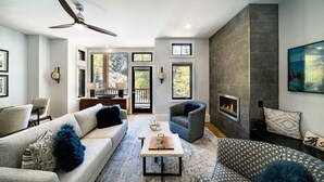 Een moderne woonkamer met een open haard, een plafondventilator en uitzicht op de omgeving.