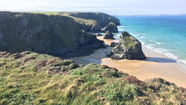 A coastal landscape with cliffs, a sandy beach, and the ocean. - Porth Farm Annexe (Newquay)