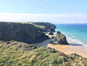 A coastal landscape with cliffs, a sandy beach, and the ocean. - Porth Farm Annexe (Newquay)