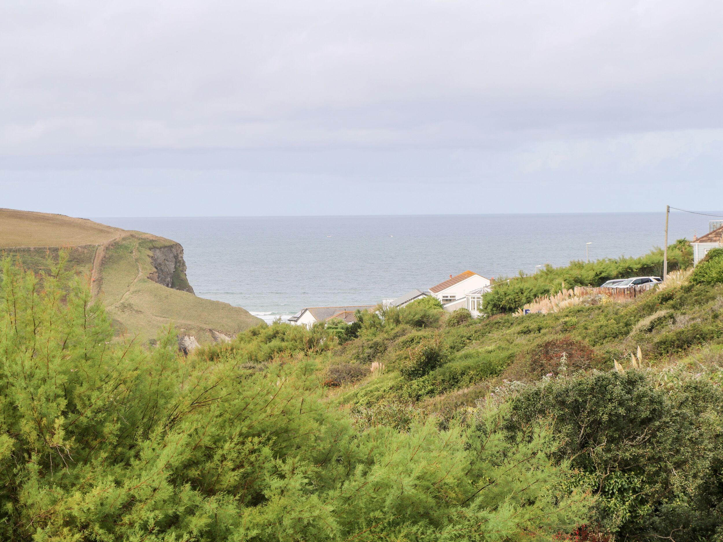 A coastal landscape with a cliff, a white building with a red roof, and a view of the sea.