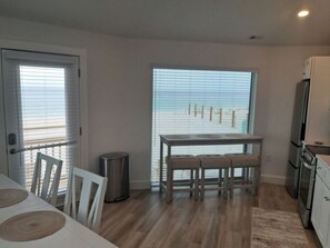 A modern kitchen with a dining area, large windows, and a view of the beach.