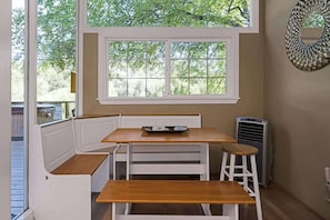 A corner room with a window, a bench, a table, and a wall-mounted mirror. - River View Lodge - Hot Tub and Tastings Included (Healdsburg)