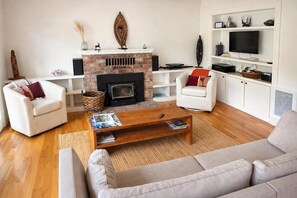 TV connectée, cheminée, livres, chaîne hi-fi