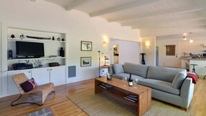 Un salon avec un canapé, une table basse, un téléviseur et des étagères.