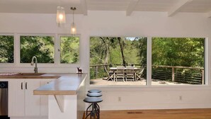 Une cuisine moderne dotée d’une grande fenêtre donnant sur une terrasse.