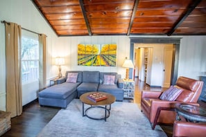 Una sala de estar con un sofá modular, una mesa de centro redonda y un sillón de cuero rojo.