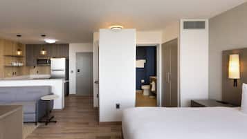 Une chambre d’hôtel moderne dotée d’une kitchenette, d’une salle de bain séparée et d’un grand lit.