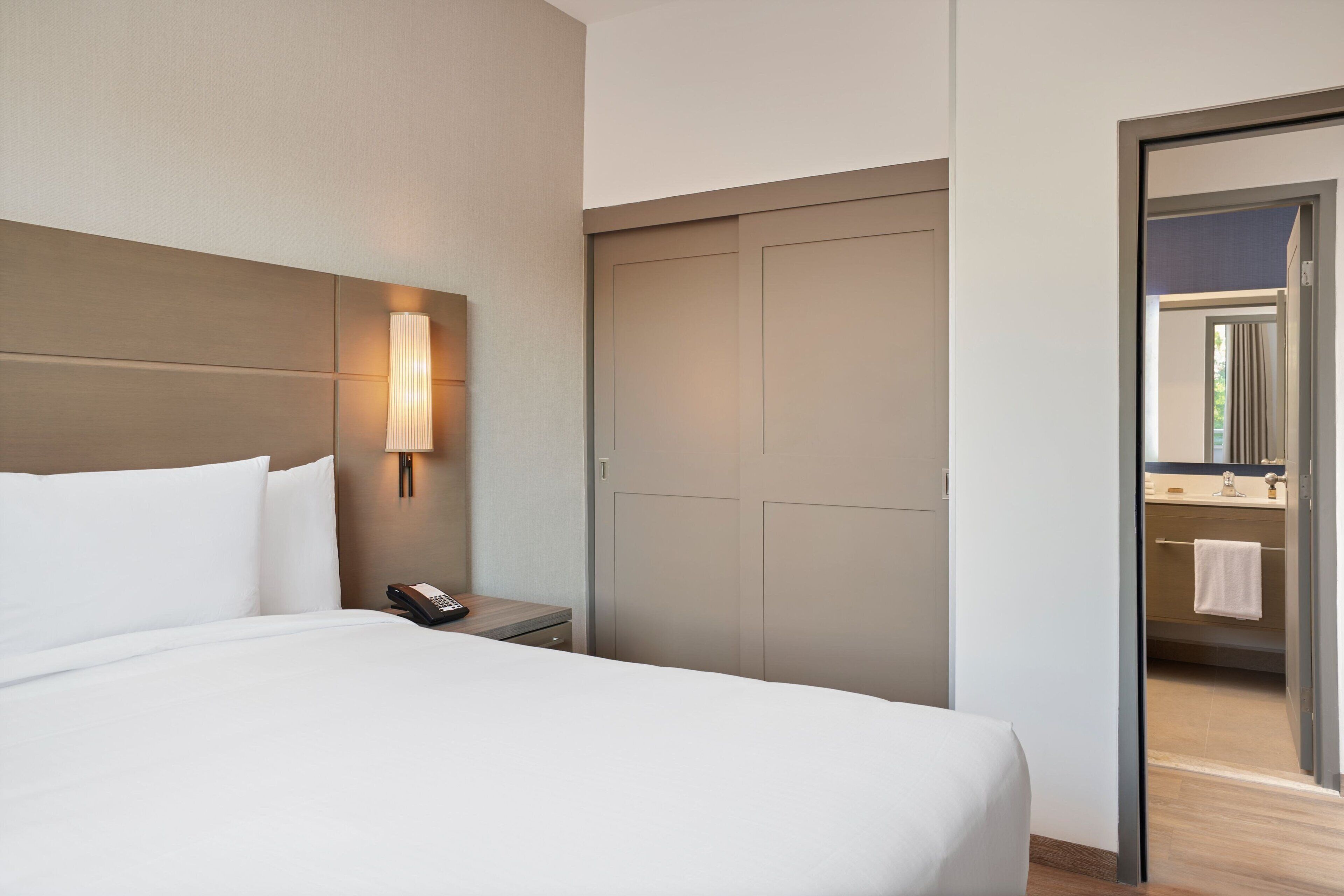 Une chambre d’hôtel avec un lit, une lampe de chevet, un téléphone et une armoire.