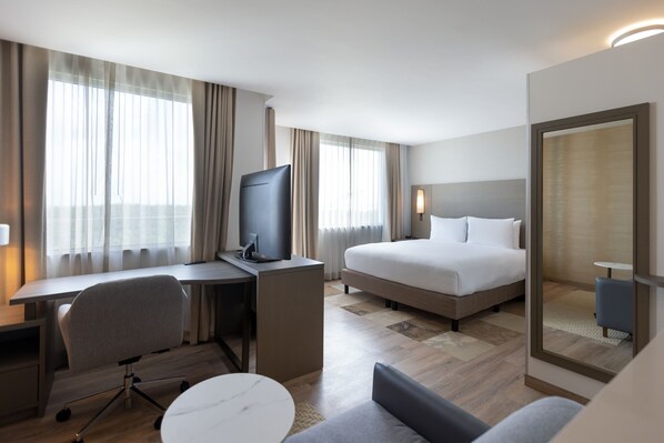 Ein Hotelzimmer mit Bett, Schreibtisch, Stuhl, Fernseher und einem kleinen Tisch.
