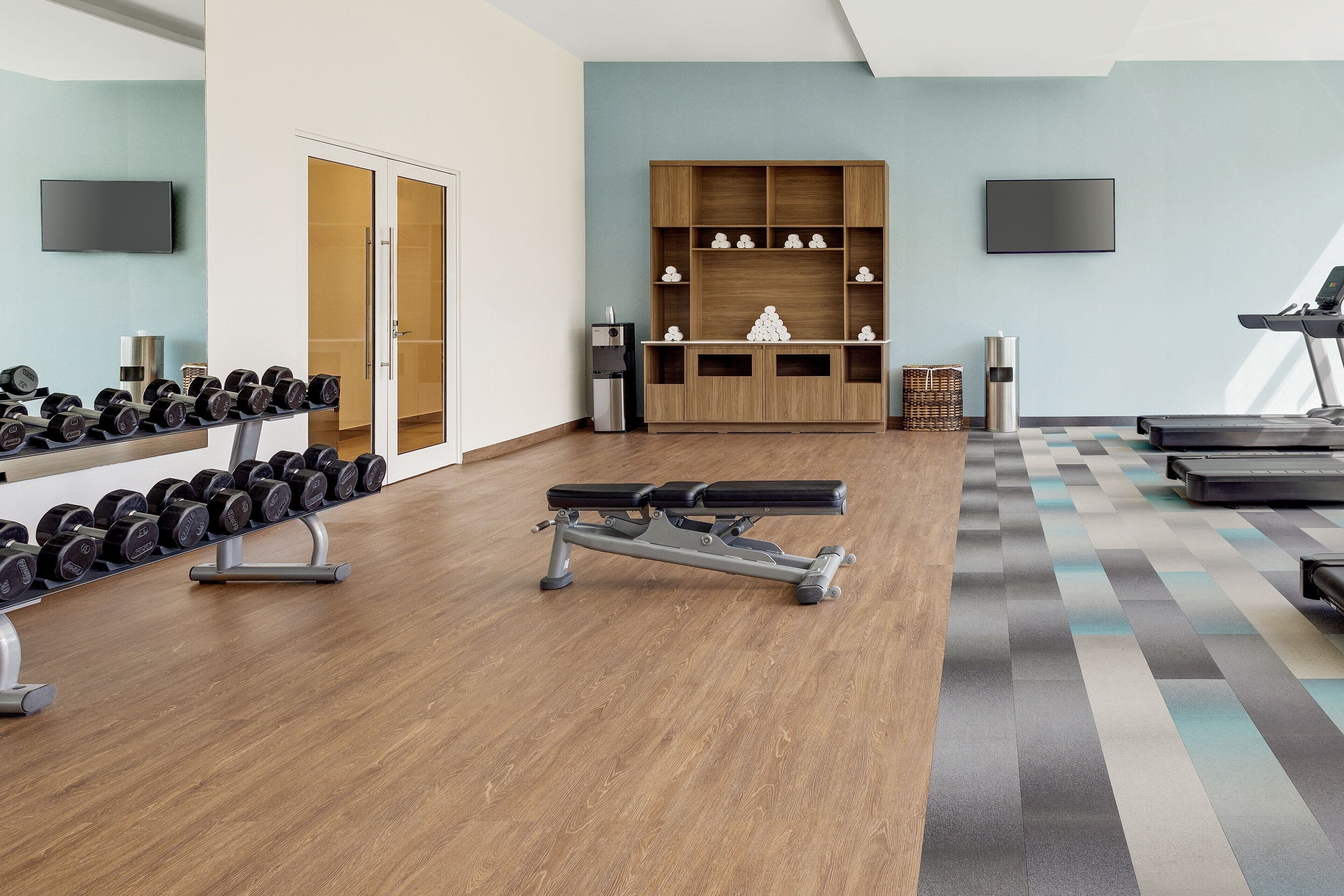 Un gimnasio con equipamiento de ejercicio, una televisión y un suelo con diseño.