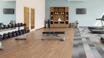 Un gimnasio con equipamiento de ejercicio, una televisión y un suelo con diseño.