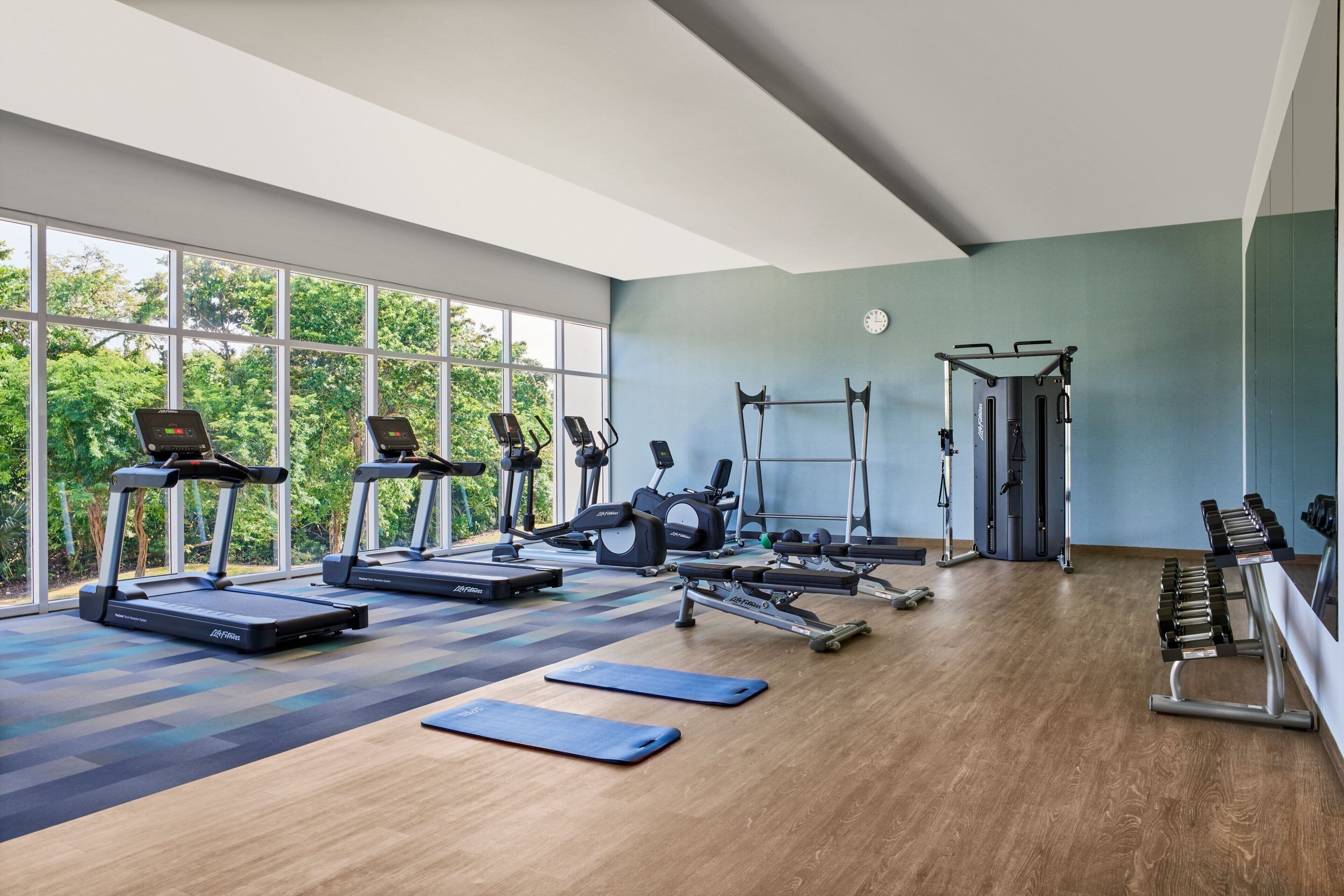 Une salle de sport équipée de tapis de course, de vélos elliptiques et de bancs de musculation.