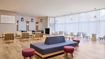A modern hotel lobby with a sofa, chairs, and tables.