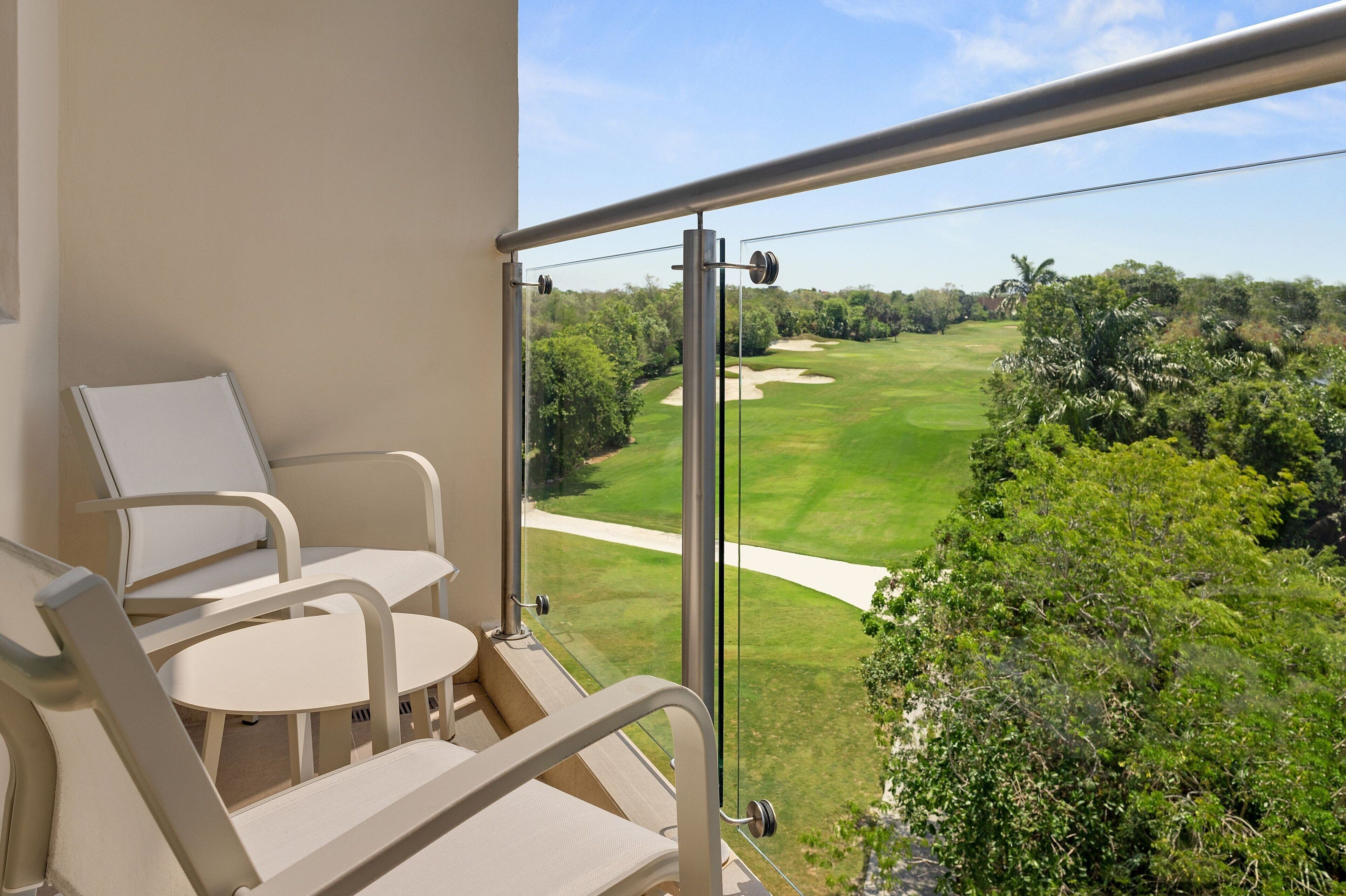 Un balcon donnant sur un terrain de golf, avec une chaise et une table.