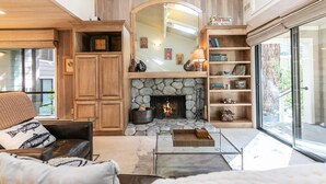 Una sala de estar acogedora con chimenea de piedra, estanterías de madera y un espejo grande en la parte superior.