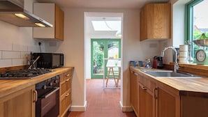 A kitchen with wooden cabinets, a stove, a microwave, and a sink.