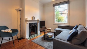 A living room with a fireplace, a sofa, a chair, a coffee table, and a lamp.