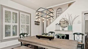 A dining area with a wooden table, benches, and chairs. There is a staircase with a railing and a decorative light fixture above the table. - Healdsburg Plaza Gem-Hot Tub and Tastings Included (Healdsburg)