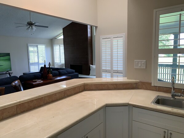 A modern kitchen with a built-in island, a dining area with a dark-colored sofa, and a fireplace.