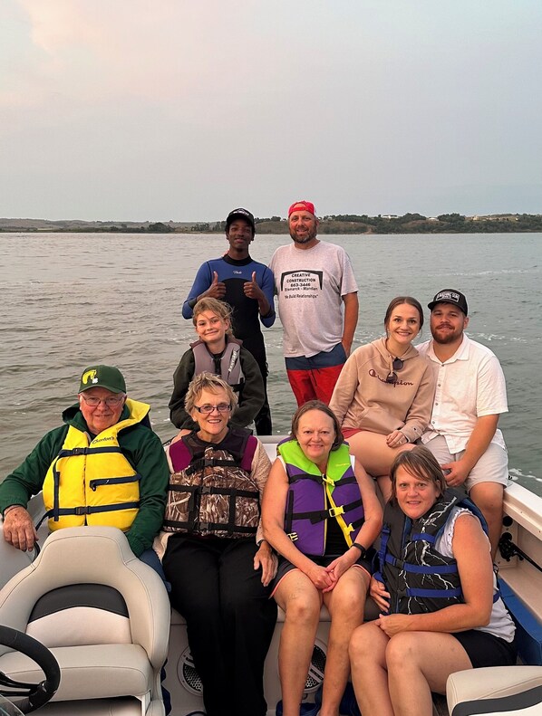 Un grupo de personas en un bote, con agua tranquila y una costa lejana al fondo.