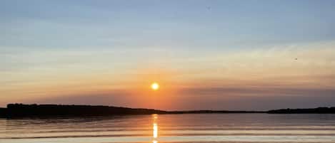 Une étendue d'eau calme où se reflète le coucher de soleil.