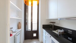 Una cocina moderna con armarios blancos, encimera negra y una lámpara colgante amarilla singular.