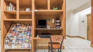 Une bibliothèque en bois contenant divers livres et magazines, un bureau avec un ordinateur et une chaise.
