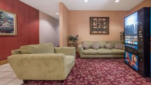 Un hall d’entrée avec un canapé vert, une moquette rouge, un tableau, un élément décoratif mural et un distributeur automatique.
