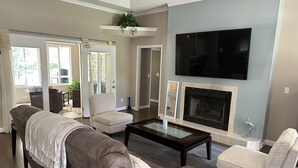A living room with a fireplace, a flat-screen TV, and a sofa. - Lake Retreat House (Anderson)