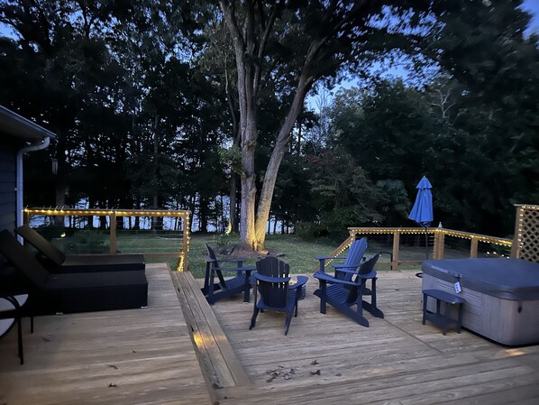 Um terraço com área de estar ao ar livre, hidromassagem e luzes de festa.