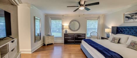 A bedroom with a bed, a ceiling fan, a dresser, a nightstand, and a mirror.