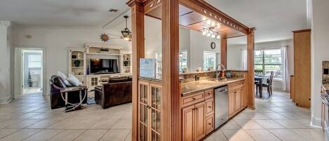 A spacious kitchen with a central island, wooden cabinetry, and a large window providing natural light.