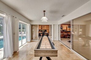Ein modernes Interieur mit einer Shuffleboard-Spieltisch, einem Essbereich und einer Küche.